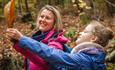 Two people looking at autumn leaves. Forestry England