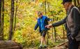 An adult pointing at a child walking along a tree trunk. Forestry England.