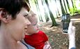 Woman with child looking at App on a mobile phone, forest setting