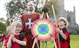 An archery target with two children holding bow and arrows with the instructor