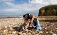 Family playing with pebbles on beach