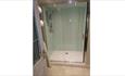 Walk in shower cubicle with spotlights in the ceiling and white towels placed on a silver towel radiator