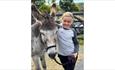 A child with her arm over a grey donkey at Bonners Lodge Caravan Park