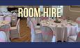 Dining room set up with round tables.  White table and chairs coverings - chairs with a pink sash.