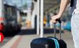 A person holding a suitcase in a bus station