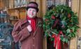 Man dressed in Victorian Clothing holding a Christmas wreath