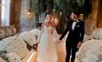 Wedding couple walking down a lit aisle with flowers at either side