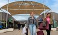 Shoppers leaving Dalton Park Outlet and Outdoors with lots of bags, smiling.