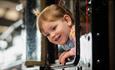 A smiling child peering out of a train window at Locomotion.