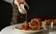 Staff pouring gravy onto Sunday Lunch.