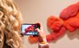 A woman taking a picture of Daisy Collingridge's artwork in From Joséphine Bowes: Trendsetters and Trailblazers exhibition.