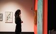 A young woman looking at a painting by Paul Merrick in From Joséphine Bowes: Trendsetters and Trailblazers exhibition.