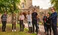 group of people listening to a tour guide outside of Durham Castle gates.