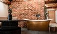 High ceilings, wood panelling, bespoke candle chandeliers and a large free-standing bath against the exposed brick wall.