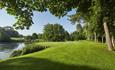 Golf green with trees down the right hand side and a large pond or lake to the left