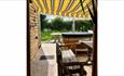View of the hot tub from the seating area outside with striped, yellow awning above.