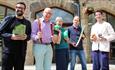 Staff standing outside of Durham Town Hall smiling, holding vegetables.