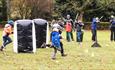 A group of children taking part in different activities. Some are running with helmets in and others are in the background preparing for archery.