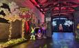 A flamingo, Mr Rabbit and the Cheshire Cat figurines in a room with blossom, fairy lights and a throne.