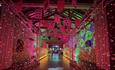 Playing cards suspended from beams in an illuminated, colourful tunnel
