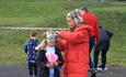 A woman placing protective goggles on a child's head, before they take part in half-term activities.