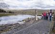 family walking along footpath beside river at Killhope