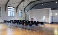 Large room with polished wood floors, beams and three rows of seating