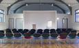 Large room with polished wood floors, beams and three rows of seating