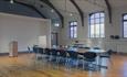 Large room with polished wood floors, beams and seating around a large table.