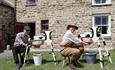 People demonstrating milking with wooden cows at Beamish Museum