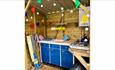 Outdoor kitchen area with blue cupboards, sink and cooking hob. Colourful bunting and fairy lights hung from the ceiling.
