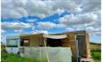 Outside view of vintage caravan with yellow awning, decking area and toilet/shower building