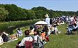 Crowds on the riverbanks enjoying Durham Regatta on a sunny day.