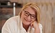 Popular TV chef and author, Rosemary Shrager, smiling, with her head resting on her hand.