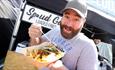 Man with beard wearing cap eating fries