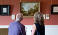 Two people looking at artwork inside Auckland Palace