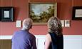 Two people viewing a painting