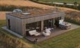 overhead shot of holiday lodge with couple sat in hot tub surrounded by countryside views.