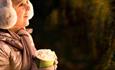 Image of a little girl wearing earmuffs enjoying a hot chocolate on The Enchanted Christmas Trail.