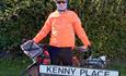 Ken Bradshaw with his bike outside of a street named 'Kenny Place'