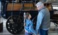 Image of a child and parent holding hands and pointing at a locomotive.