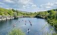 A group of paddleboarders in the distance. Paddle boarding on the water surrounded by greenery