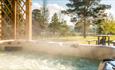 View from a steaming hot tub with trees and a picnic table in the distance.