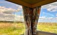 View of the countryside from the 2 windows with floral curtains