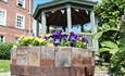 tub of flowers, covered seating area to rear of St Johns College