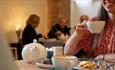 a visitor having tea and scones at the Bishop's Kitchen