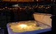 Fairy lights around warmly lit hot tub at night - Beamish Glamping.