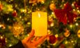 woman's hand holding a candle in front of Christmas decorations.