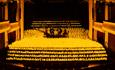 Group of musicians on a stage playing string instruments surrounded by hundreds of candles.