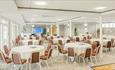 Room set out for a conference with round tables and chairs